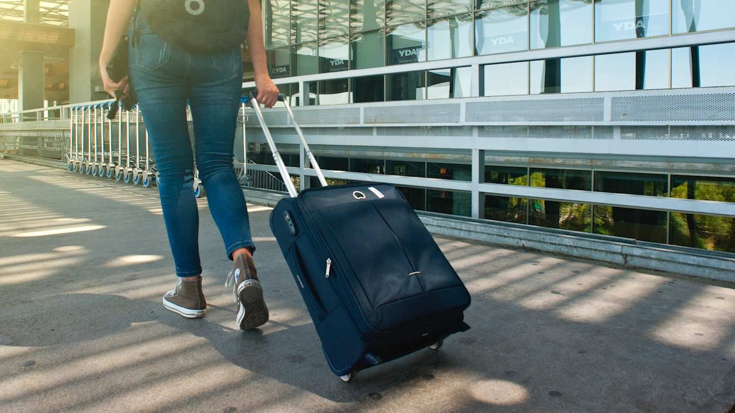 Person walking along pavement with luggage bag