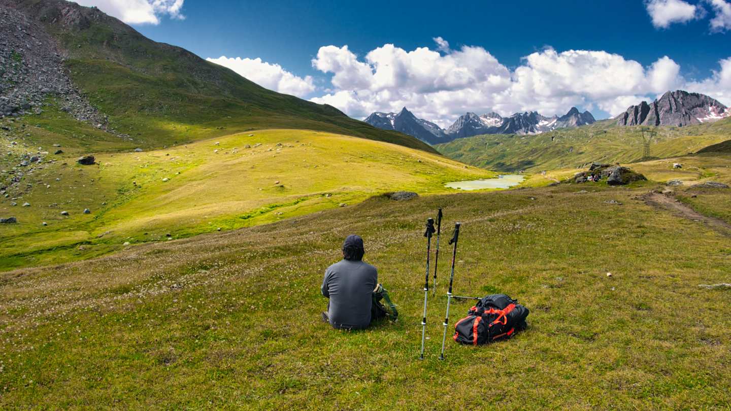 Person sitting down admiring the view after hiking in the mountains, Switzerland