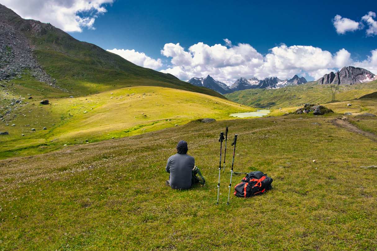 Person sitting down admiring the view after hiking in the mountains, Switzerland