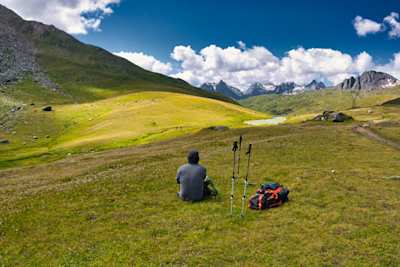 Person sitting down admiring the view after hiking in the mountains, Switzerland
