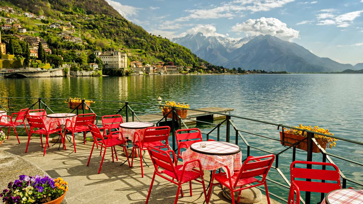 Red tables and chairs outside a cafe next to Lake Como, Lombardy, Italy