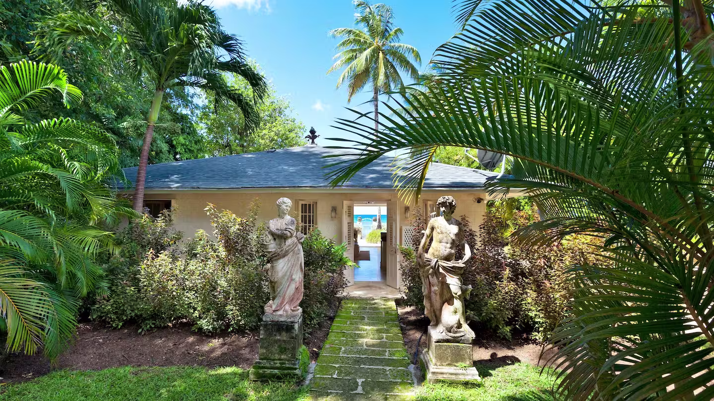 Palm trees and statues flanking the entranceway to Plum Guide Home 'As the Tide Rolls In', Barbados