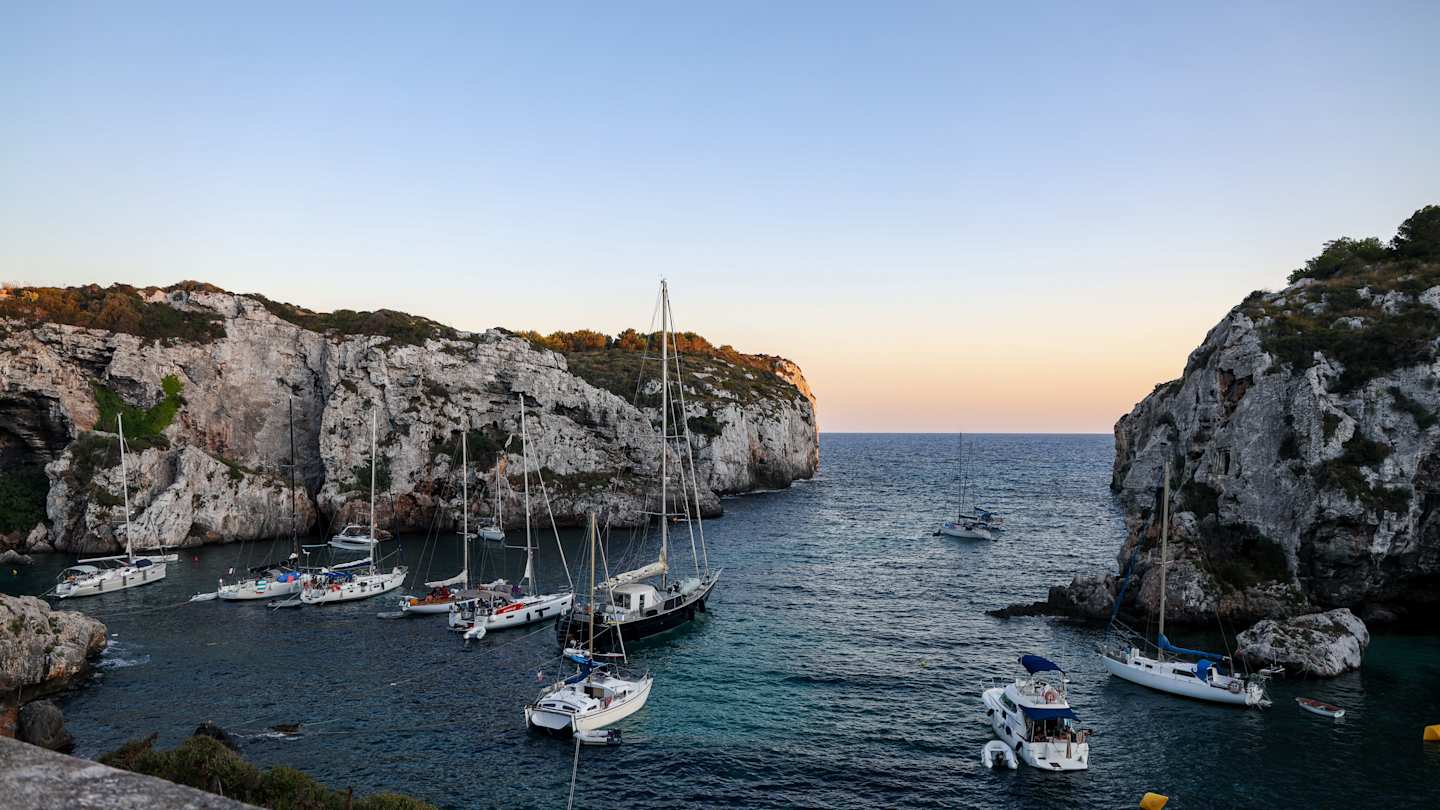 A beach in Menorca with boats on the water