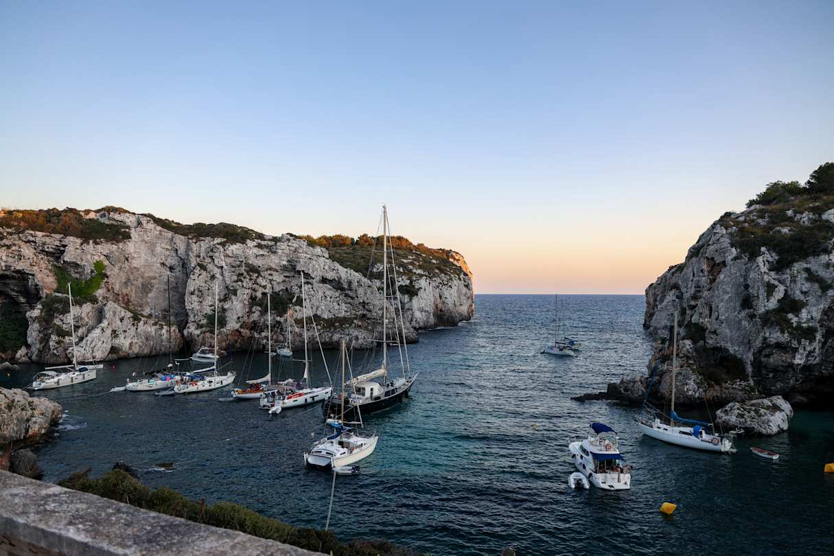 A beach in Menorca with boats on the water