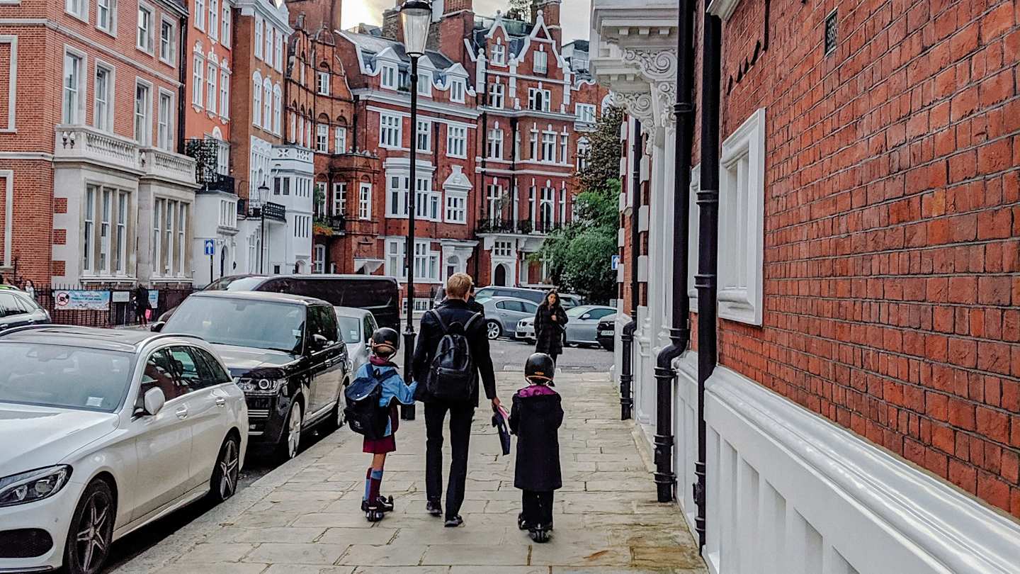 Children and adult walking along pavement in London