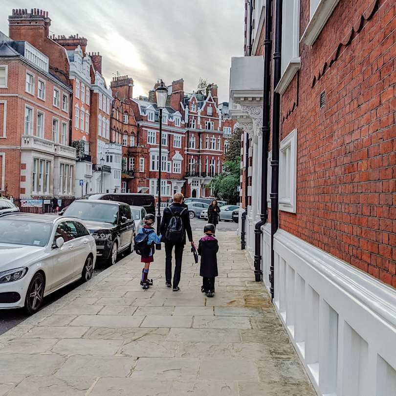 Children and adult walking along pavement in London