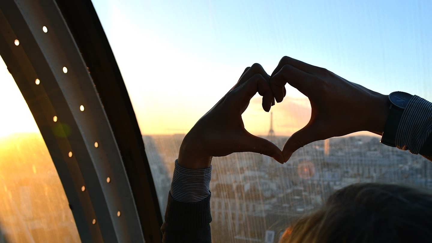 Person shaping a heart with their hands in Paris
