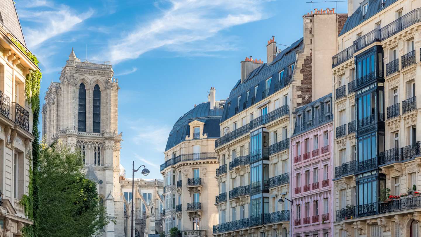 Charming buildings with typical Parisian facades in Le Marais, with Notre-Dame cathedral in background, Paris, France