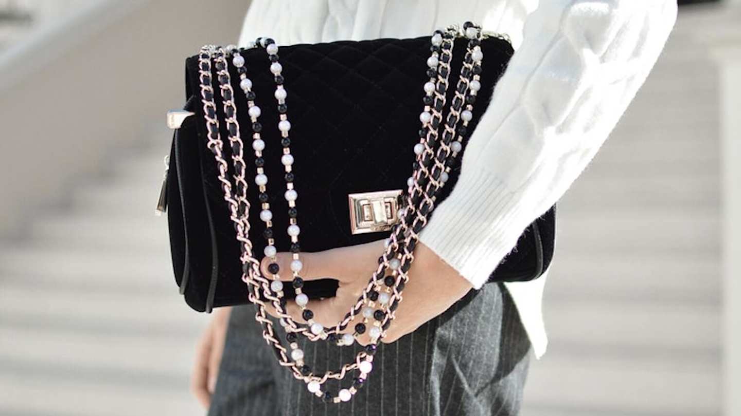 Person holding black handbag with decorative strap