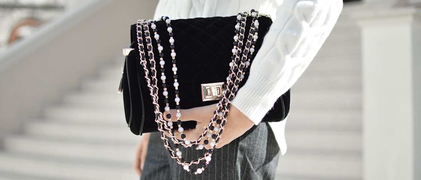 Person holding black handbag with decorative strap