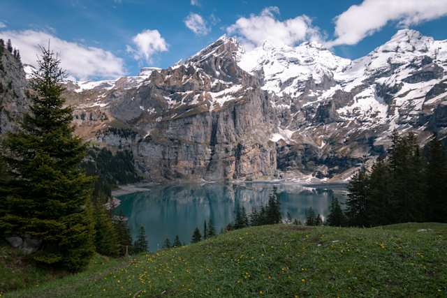 A still blue lake at the foot of large snow-capped mountains in Switzerland