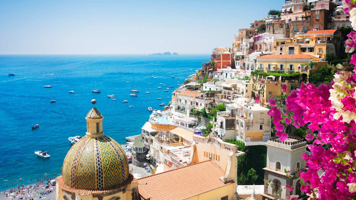 View of Positano's cliffside houses and clear blue sea, with flowers in foreground, Amalfi Coast