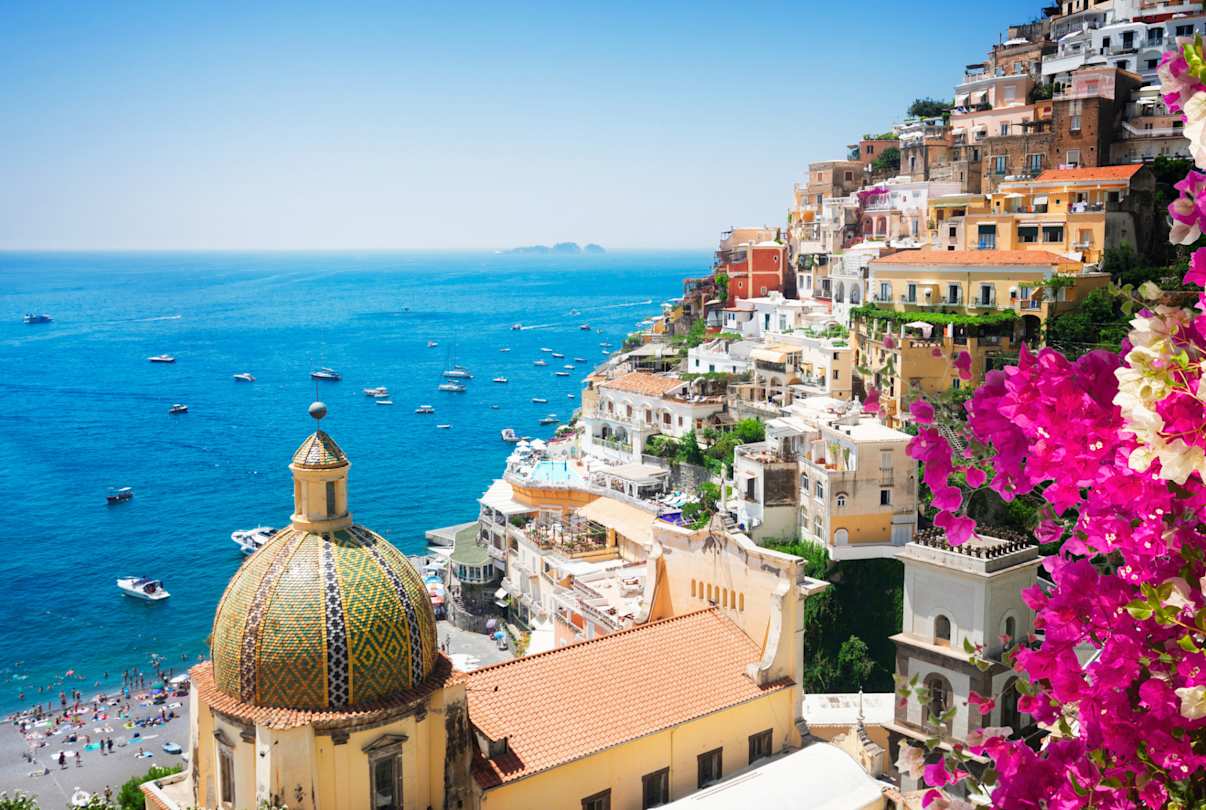 View of Positano's cliffside houses and clear blue sea, with flowers in foreground, Amalfi Coast