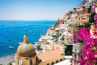 View of Positano's cliffside houses and clear blue sea, with flowers in foreground, Amalfi Coast