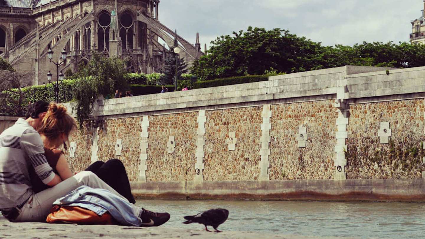 Couple sat along the Seine in Paris