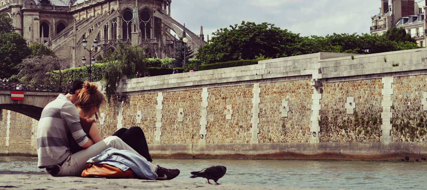 Couple sat along the Seine in Paris