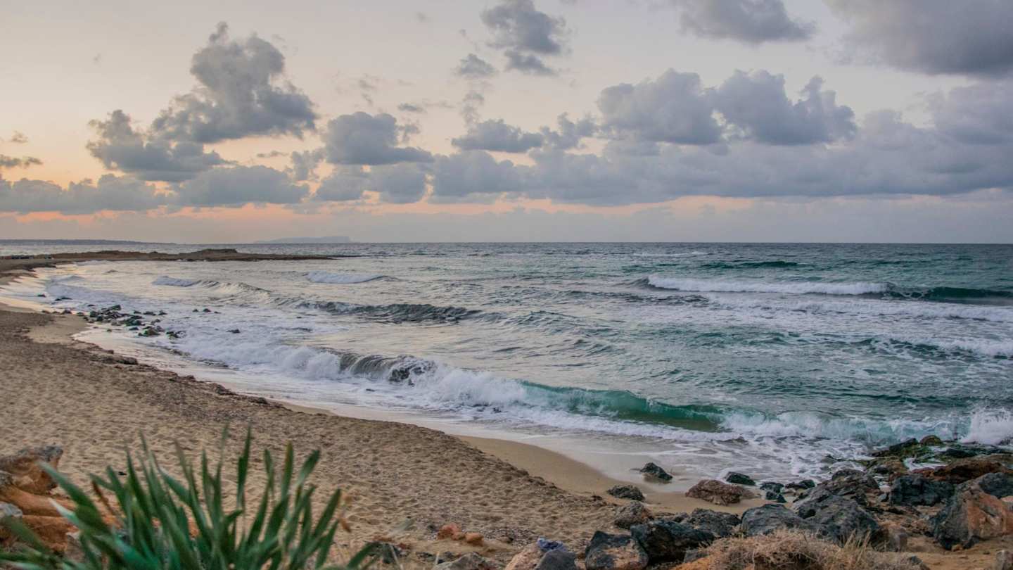Waves crashing onto the sand at a beach in Malia at sunset, Crete, Greece