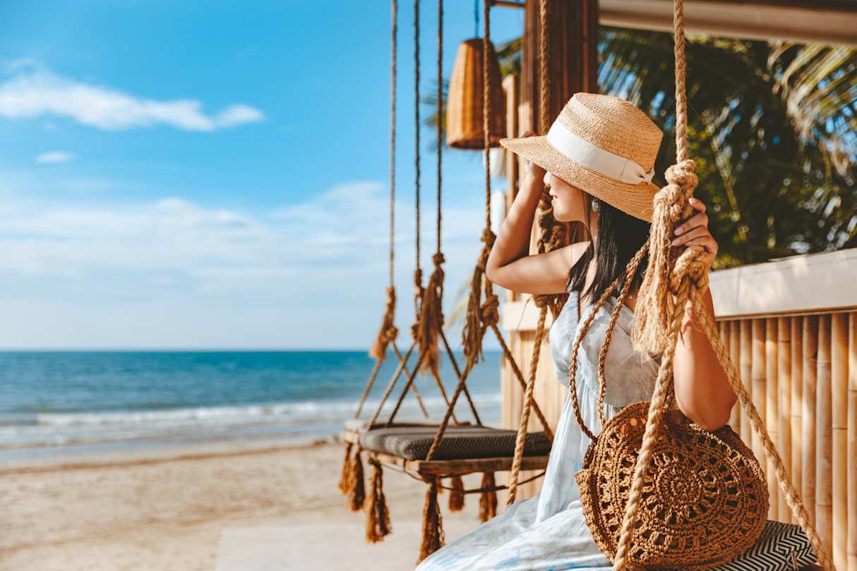 A woman sitting on a relaxing swing at the beach in a hot destination