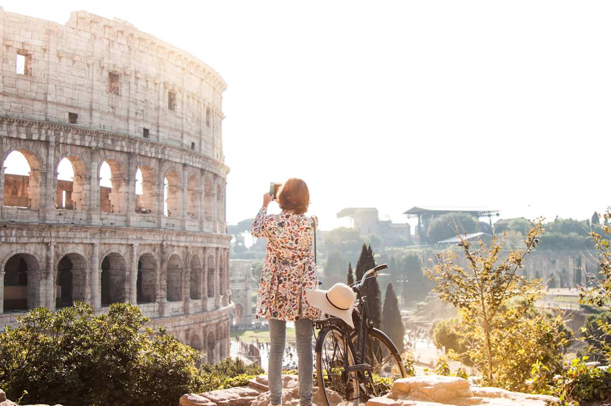 A woman with a bicycle taking a picture of the Colosseum on a solo travel trip, Rome, Italy