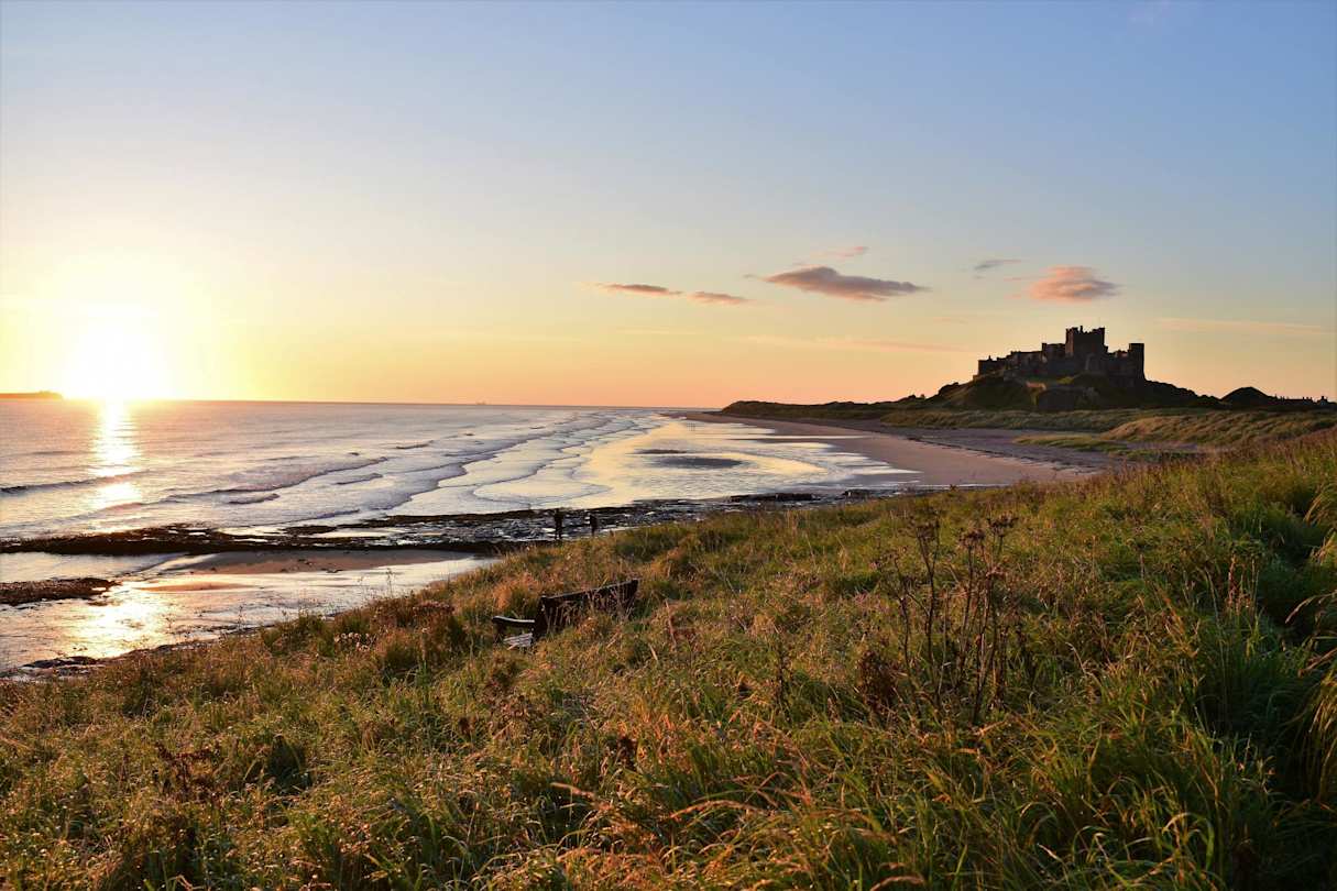 A wide-angle shot of the beach in Bamburgh, with the castle in the distance at sunset, Northumberland, England, UK 
