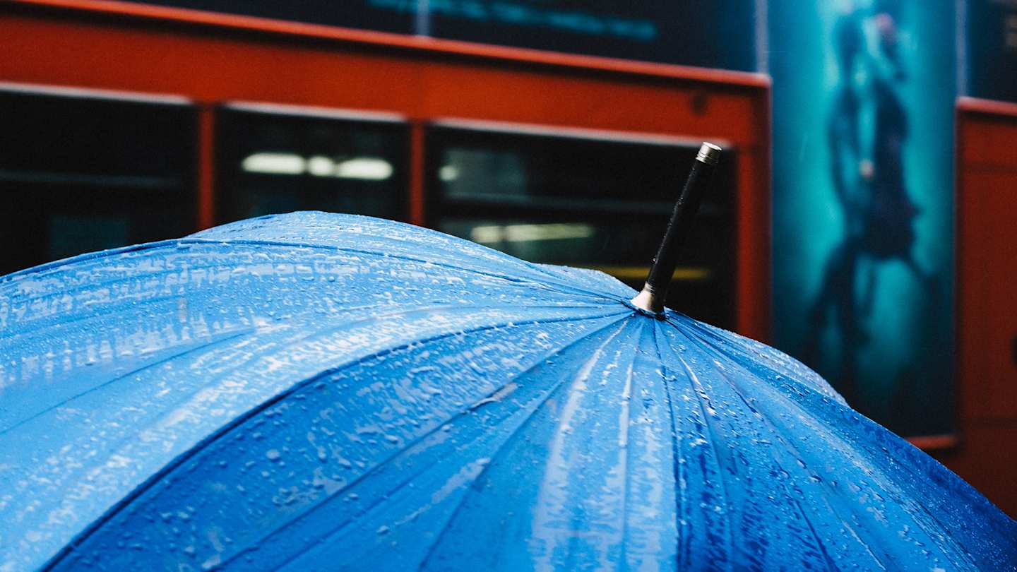 Umbrella in front of red London bus