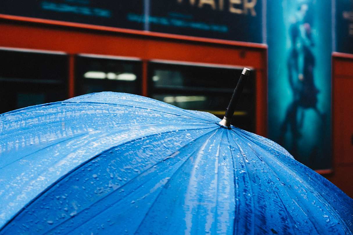Umbrella in front of red London bus