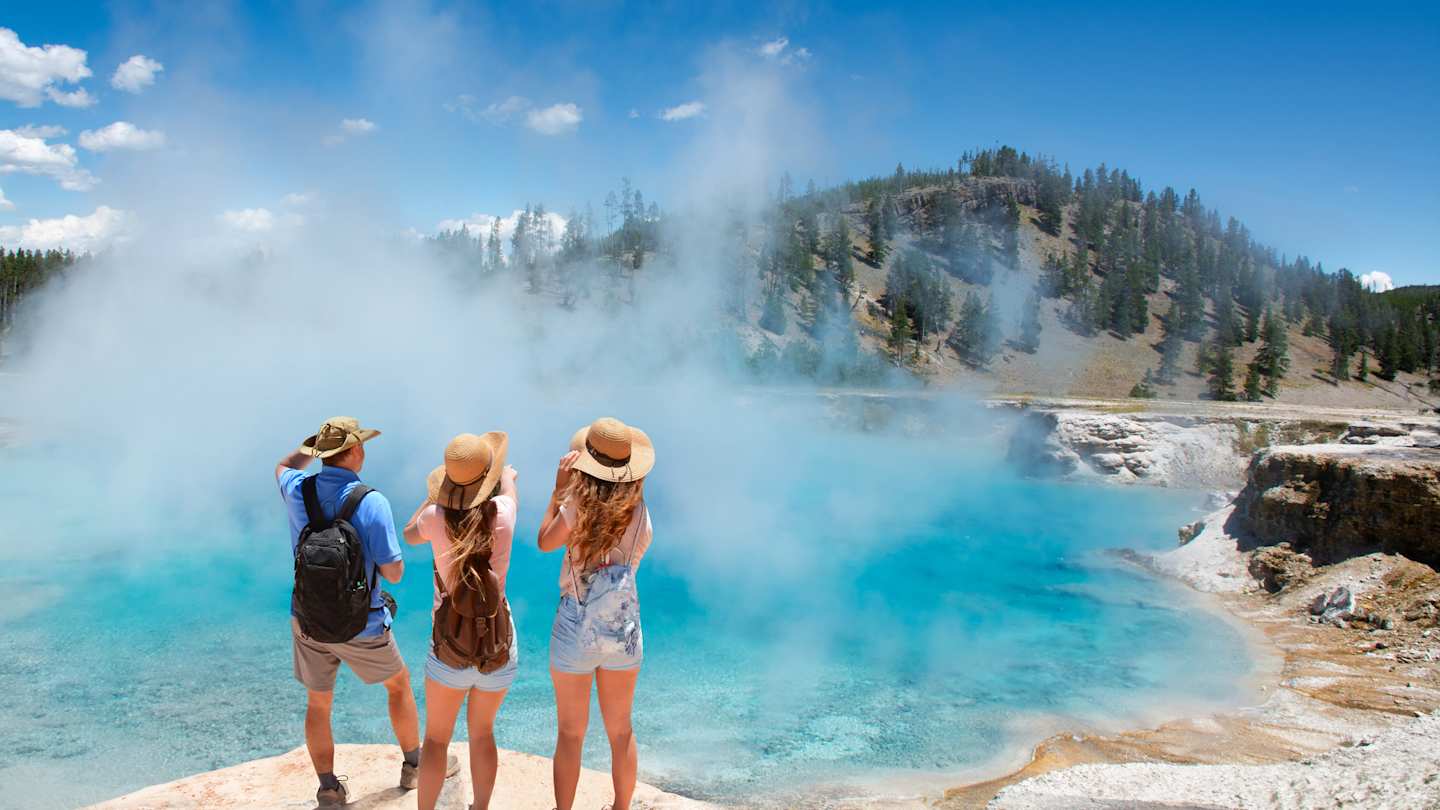A family admiring the hot springs on a sunny day at Yellowstone National Park, USA