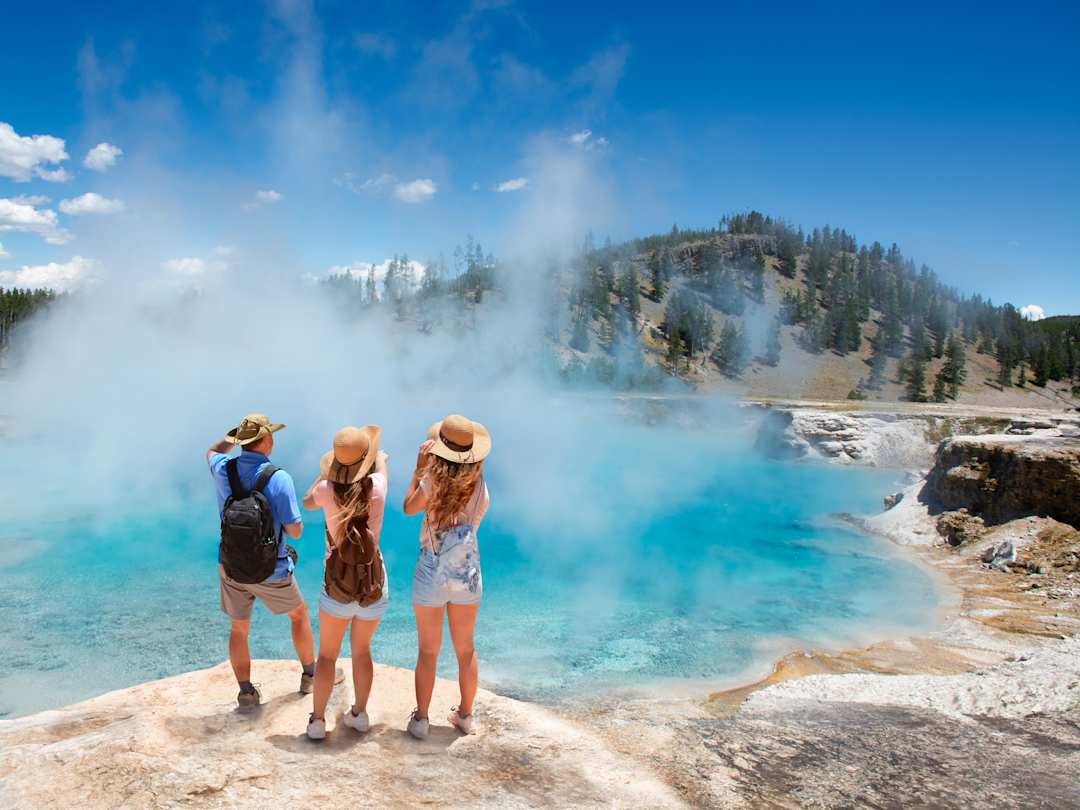 A family admiring the hot springs on a sunny day at Yellowstone National Park, USA