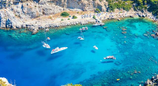An aerial view of boats on the clear blue water at Anthony Quinn Bay, Rhodes, Greece