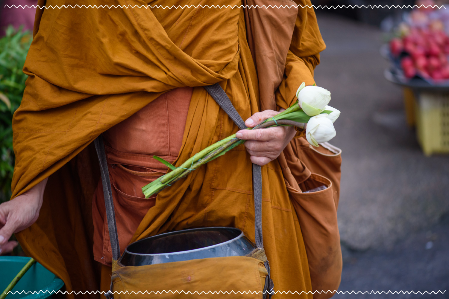 man in monk clothing holding white flowers