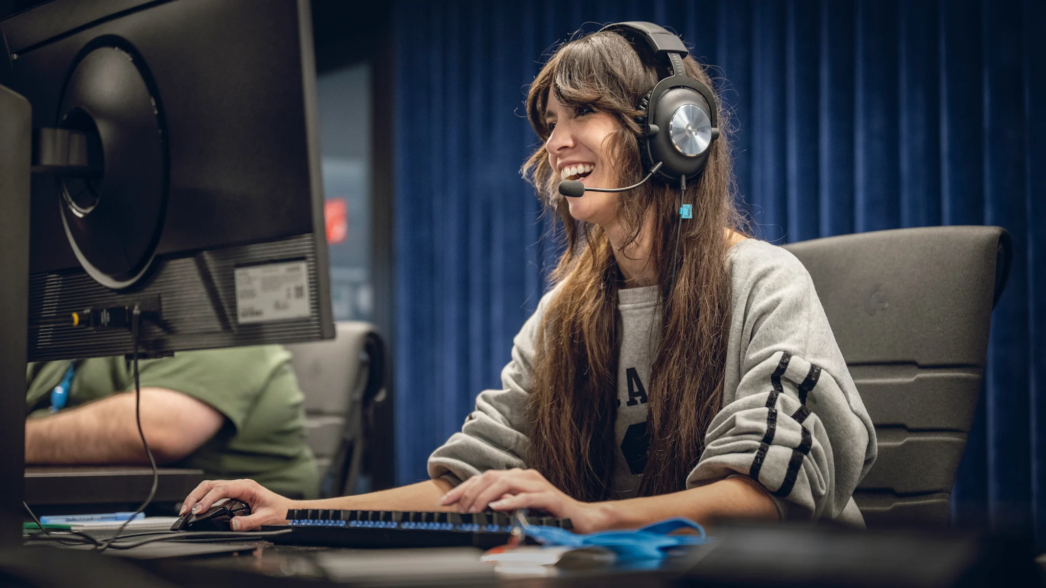 A female gamers tests March of Giants while wearing a headset and a huge smile