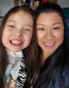 A BAYADA caregiver and a young girl, both smiling brightly, pose closely for a selfie. The background is indoors, creating a warm and joyful atmosphere.
