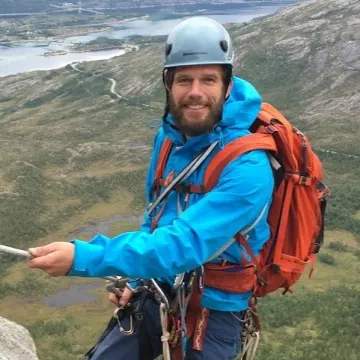Esben Kuhnt is a mountain climber and is in he's gear hanging from a wall