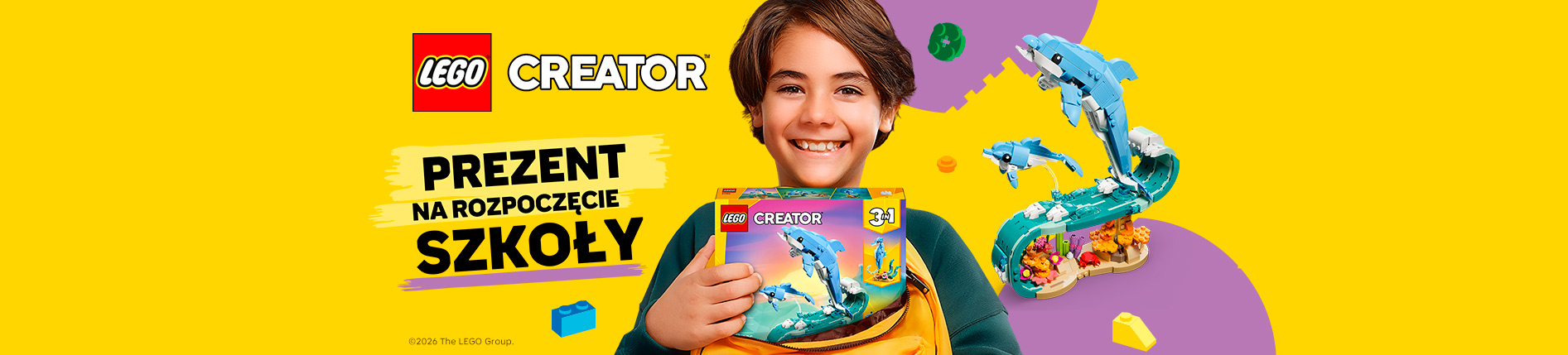 Uśmiechnięte dziecko trzyma plecak z zestawem LEGO Creator 3 w 1 z delfinem. Na grafice widoczne są logo LEGO Creator oraz hasło „Prezent na rozpoczęcie szkoły” na żółtym tle z kolorowymi klockami.