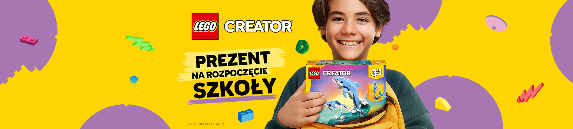 Uśmiechnięte dziecko trzyma plecak z zestawem LEGO Creator 3 w 1 z delfinem. Na grafice widoczne są logo LEGO Creator oraz hasło „Prezent na rozpoczęcie szkoły” na żółtym tle z kolorowymi klockami.
