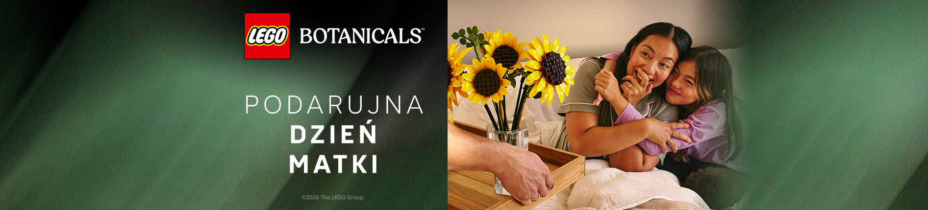Reklama LEGO Botanicals na Dzień Matki. Po lewej logo LEGO Botanicals i tekst "Podaruj na Dzień Matki" na zielonym tle. Po prawej uśmiechnięta kobieta i dziecko przytulające się, obok wazon z żółtymi słonecznikami.