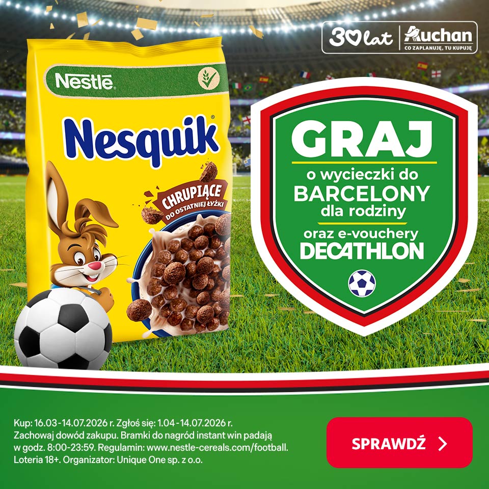 Baner reklamowy Nesquik na tle stadionu piłkarskiego. Przedstawia żółte opakowanie płatków Nesquik z królikiem i piłką, obok zielony szyld "GRAJ" oferujący wycieczki do Barcelony i e-vouchery Decathlon. W tle logo "30 lat Auchan".