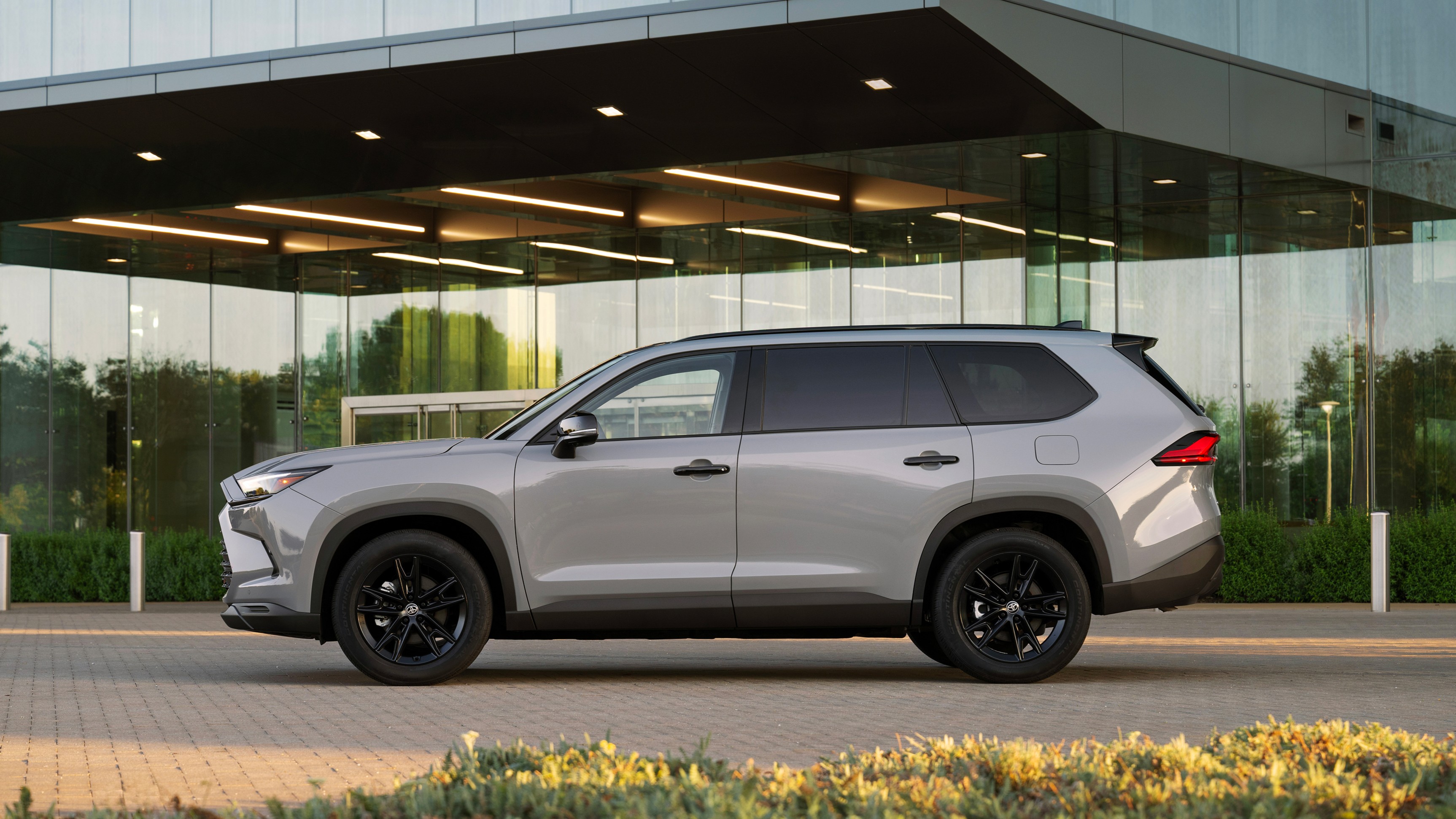 A sleek 2026 Toyota Grand Highlander parked against a scenic backdrop, showcasing its modern design and spacious three-row interior.