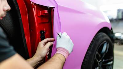 Car wrap specialist putting vinyl foil or film on car.
