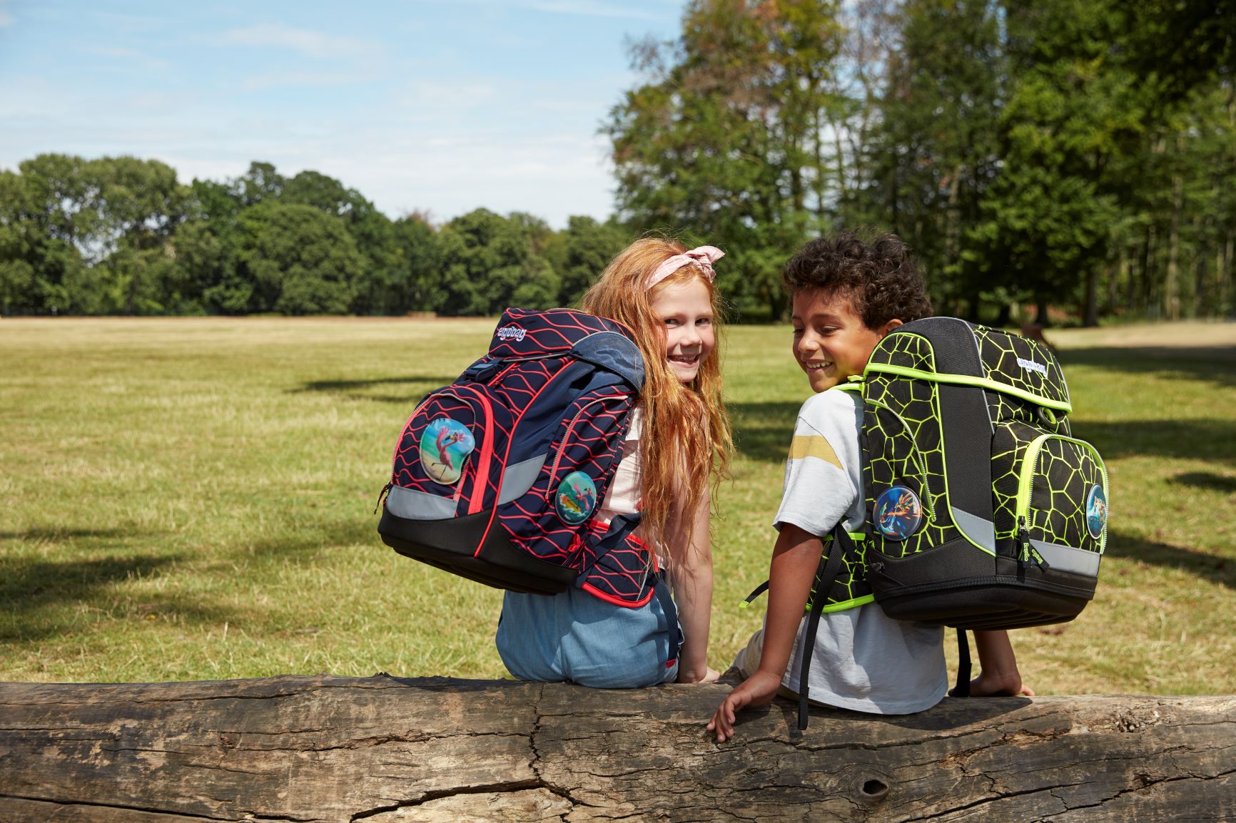 Ergobag 1.0 Outdoor Junge und Mädchen sitzen auf Baumstamm