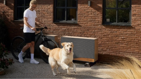 Quatt 14kw monoblock buitenunit tegen gevel geplaatst man loopt er langs met fiets en golden retriever hond rent