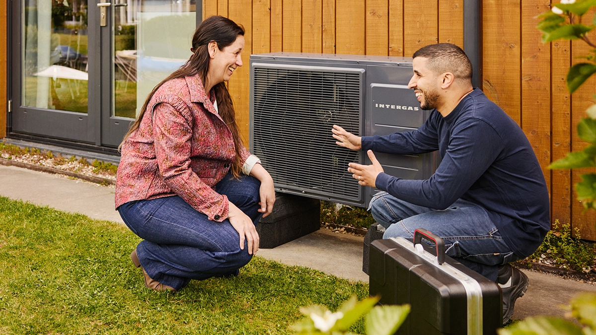 Intergas Xtend Split warmtepomp buitenunit tegen gevel aan installateur legt iets uit aan een vrouw