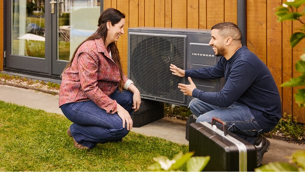 Intergas Xtend Split warmtepomp buitenunit tegen gevel aan installateur legt iets uit aan een vrouw