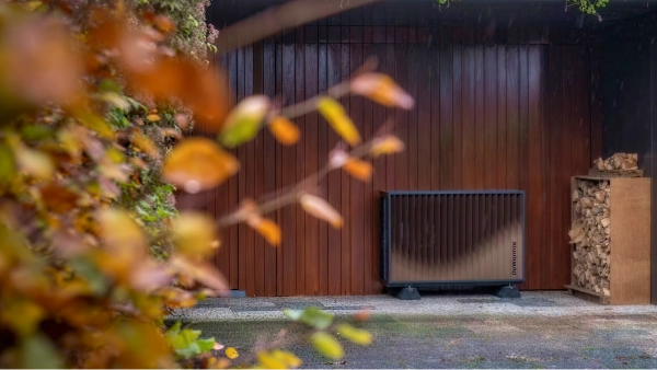 DeWarmte Pomp MP All electric warmtepomp buitenunit tegen de gevel naast een houthok