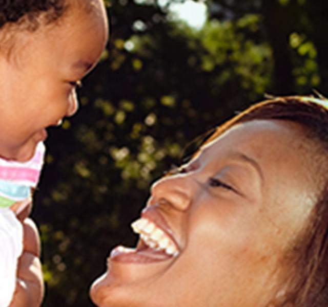 Woman holding a baby in her hands, man standing behind her