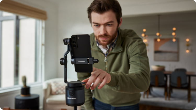 Un hombre manejando un Matterport Axis con un teléfono en un trípode.