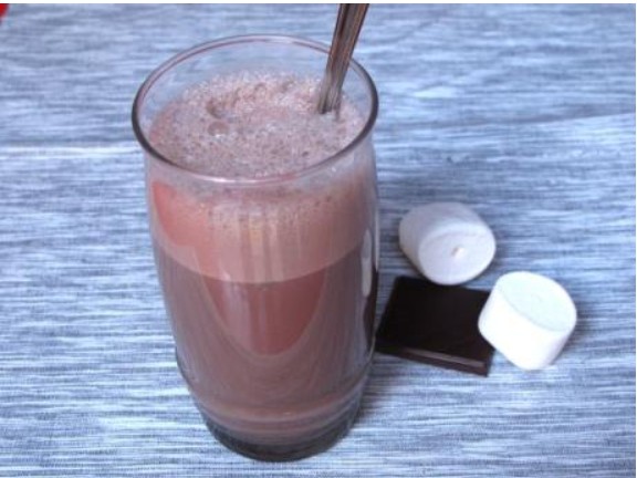Vaso alto con batido de chocolate casero cremoso y una pajita en una cocina familiar, receta infantil fácil de Alcampo.
