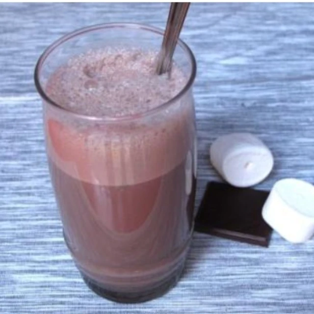 Vaso alto con batido de chocolate casero cremoso y una pajita en una cocina familiar, receta infantil fácil de Alcampo.