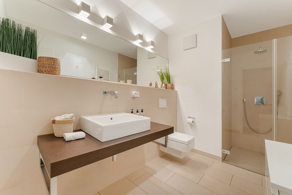 Modernes Badezimmer mit großem Waschbecken, begehbarer Dusche und Dekorationen aus Pflanzen und Körben.