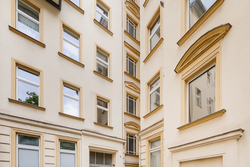 Innenhof eines mehrstöckigen Wohngebäudes mit vielen Fenstern und beigen Fassaden.